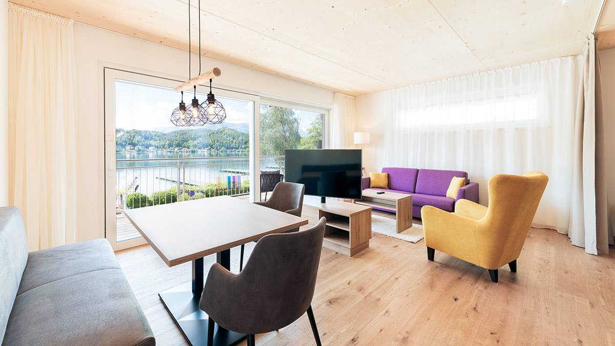 Wohn-Esszimmer mit großem Fenster und Seeblick, moderne Ausstattung.