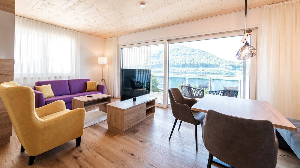 Wohn-Esszimmer mit großem Fenster und Seeblick, moderne Ausstattung.
