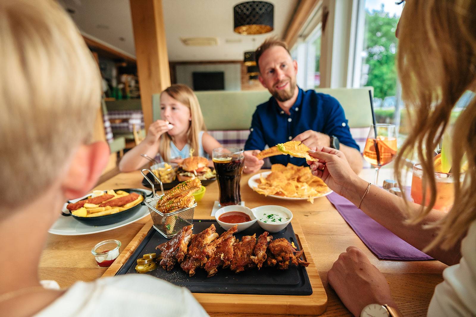 Eine Famiie genießt das Essen im Restaurant beim Apartmethaus Seewirt am Klopeiner See.