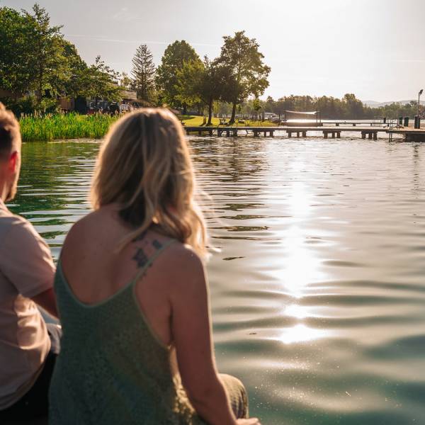 Paar sitzt am Steg uund schaut auf den See