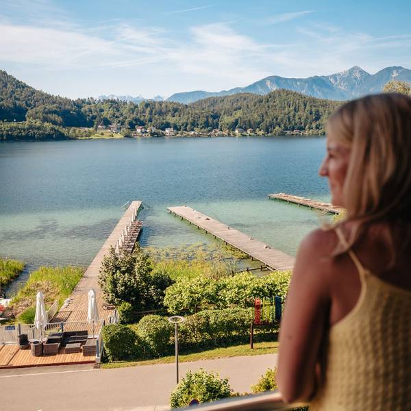 Frau steht am Balkon und blickt auf den Klopeiner See